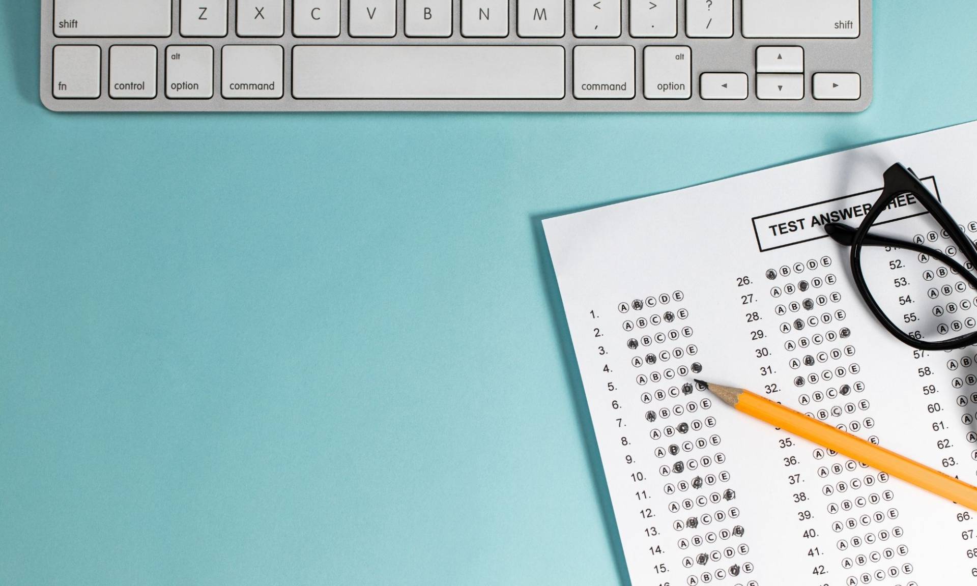Computer keyboard and test answer sheet with pencil and eyeglasses.